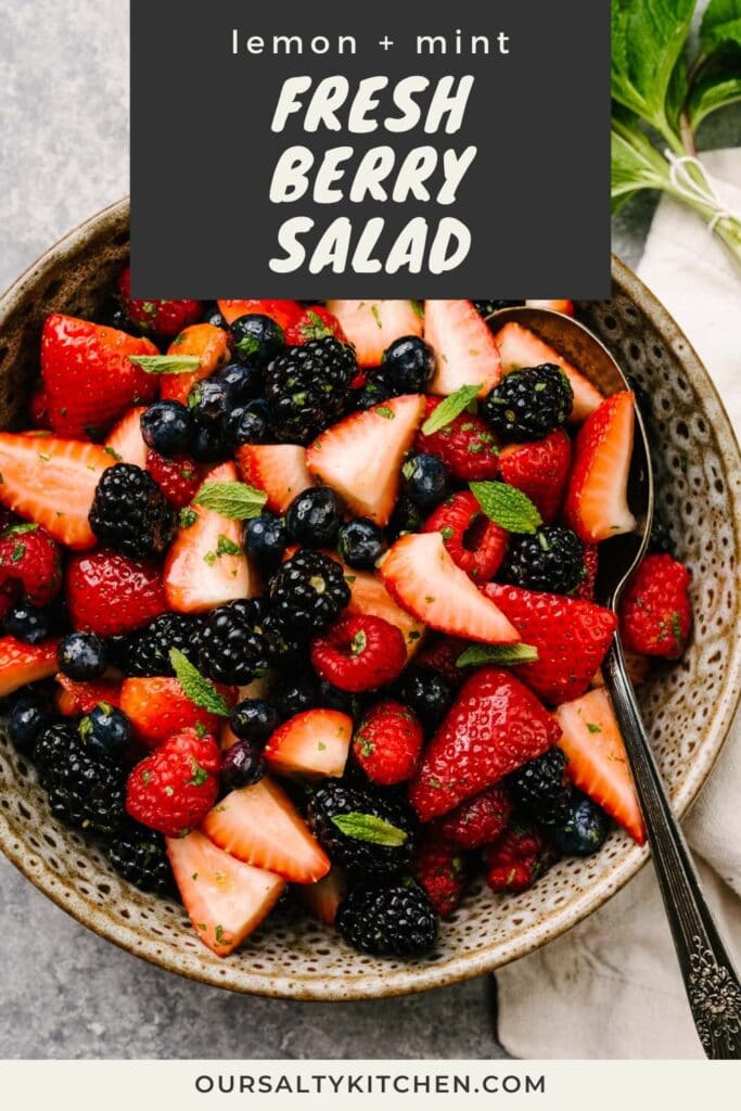 A berry fruit salad made with strawberries, blueberries, blackberries, raspberries, mint, and lemon honey dressing in a brown speckled bowl with a cream linen napkin to the side; title bar at the top reads "lemon and mint fresh berry salad".