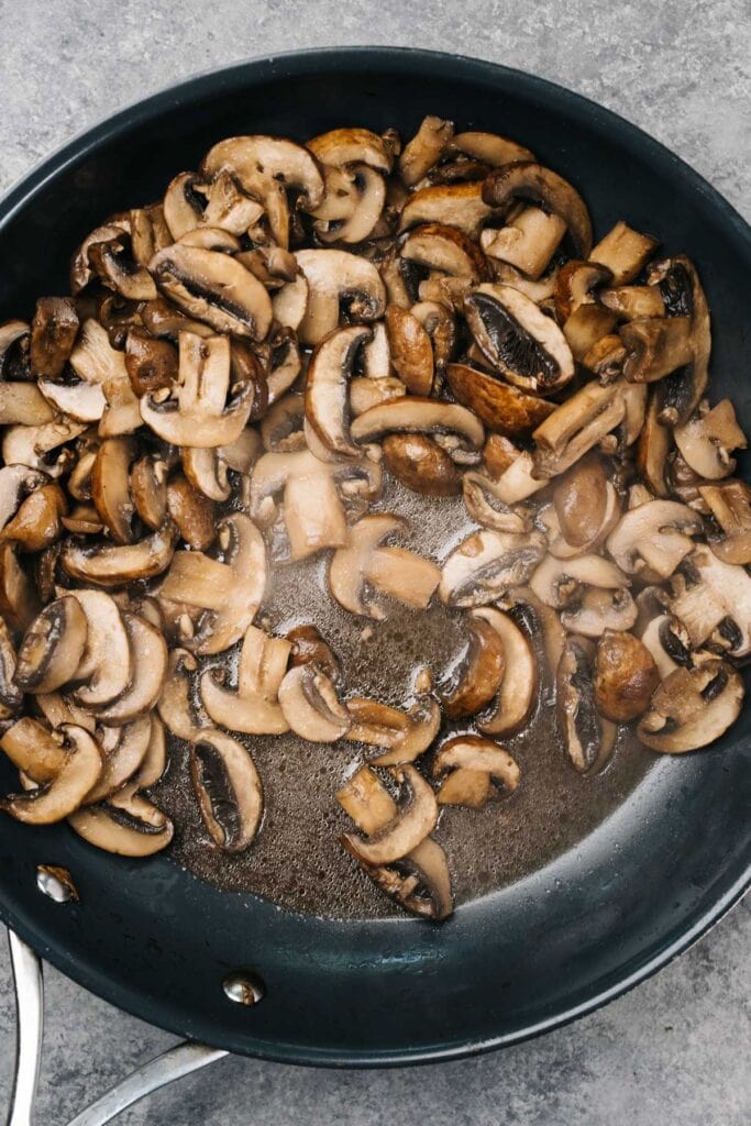Mushrooms sauteeing in a skillet around the halfway cooking mark - the mushrooms have released a ton of liquid and are very soft.