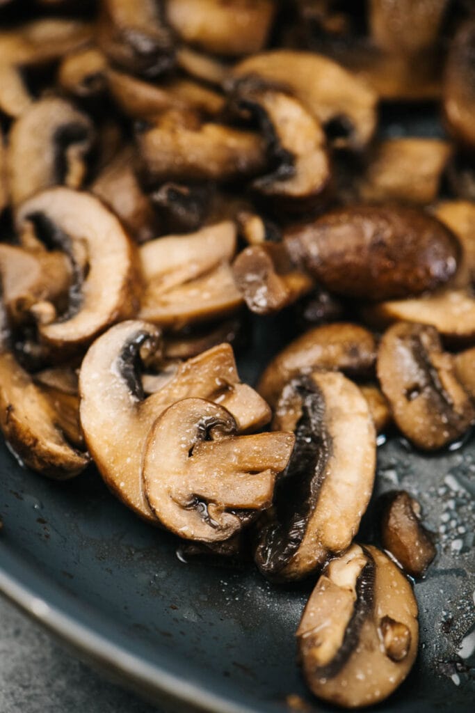 Sauteed mushrooms in a skillet just after the remaining moisture has been cooked off, but before the edges have turned golden brown.