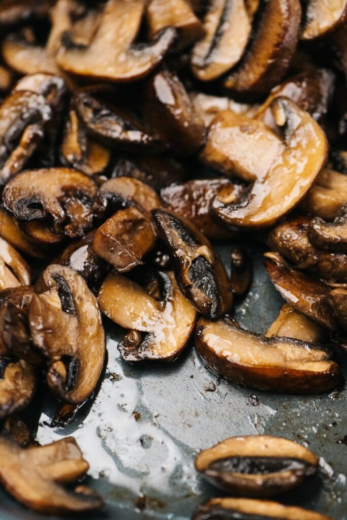 Side view, sauteed golden brown mushrooms in a skillet showing crispy edges and no remaining liquid in the pan.