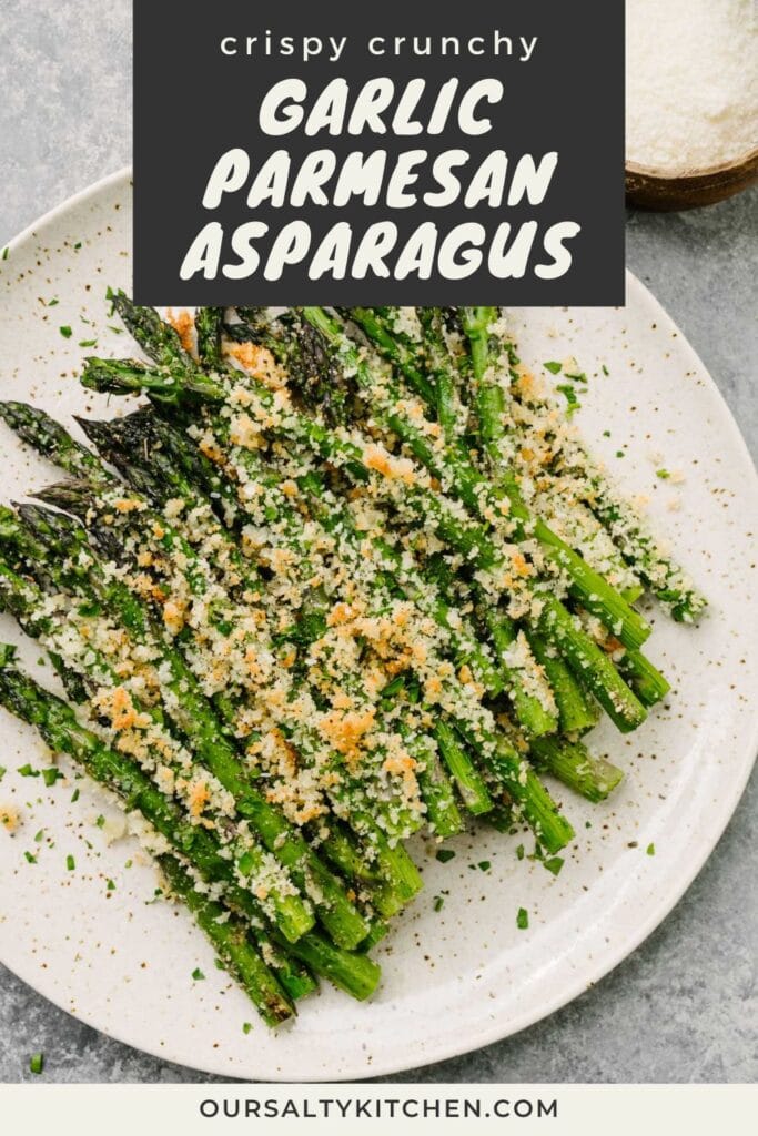 Roasted asparagus with parmesan on a brown speckled plate on a concrete background, with a small bowl of grated parmesan cheese to the side; title bar at the top reads "crispy crunchy garlic parmesan asparagus".