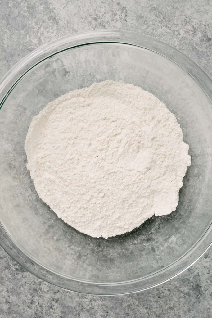 All purpose flour, sugar, baking powder, salt, and cinnamon whisked in a large glass mixing bowl until well combined.