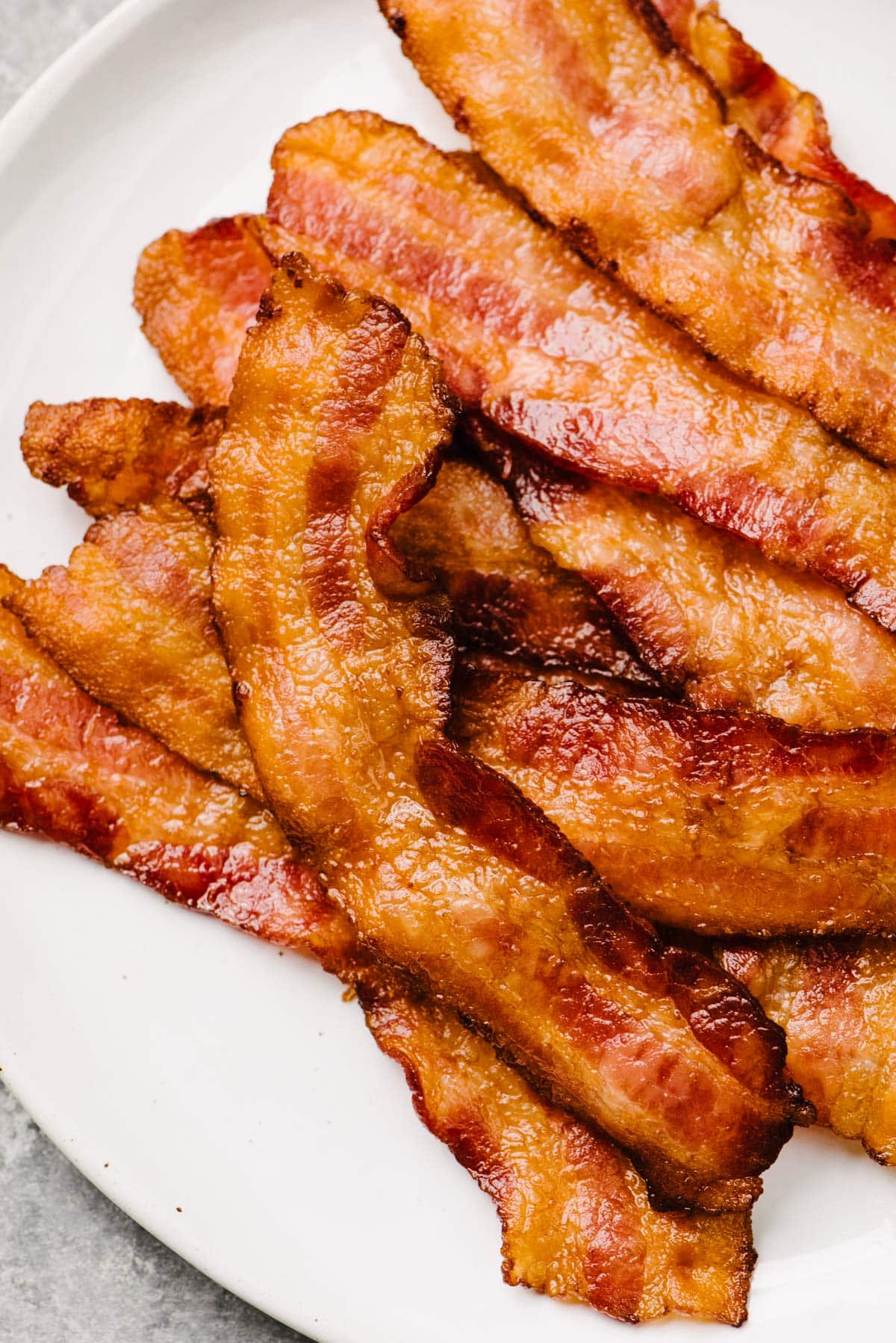 Close-up view of crispy oven cooked bacon on a white plate.