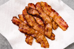 Crispy oven baked bacon strips on a paper towel lined plate.