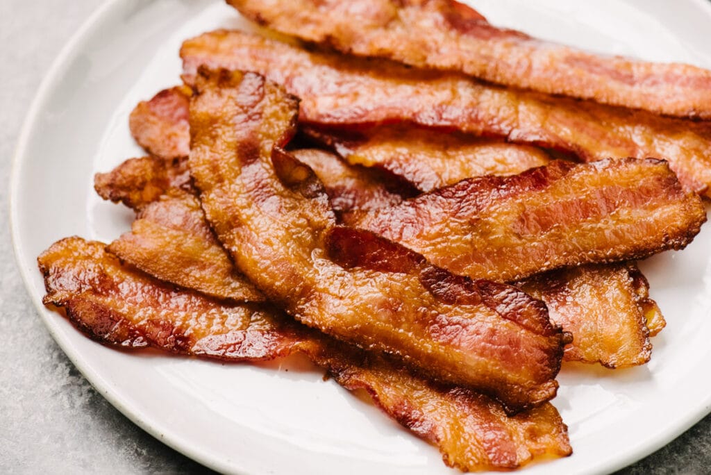 Side view, crispy oven baked bacon on a white plate.