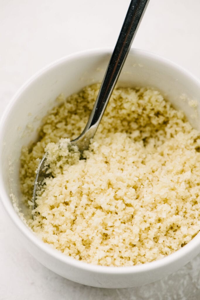 Side view, panko bread crumbs mixed with melted butter in a small white bowl.