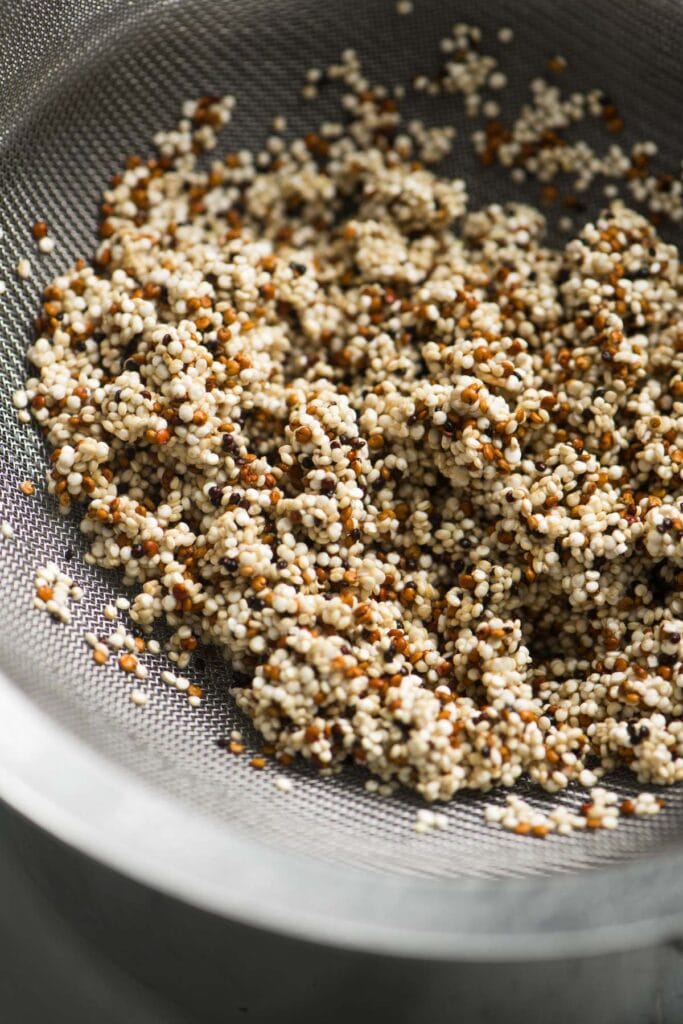 Side view, rinsed quinoa in a fine mesh sieve.