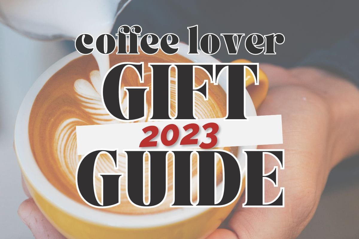 Side view, a hand holding a cappuccino cup with another hand pouring foam on top; text overlay reads "coffee lover 2023 gift guide".