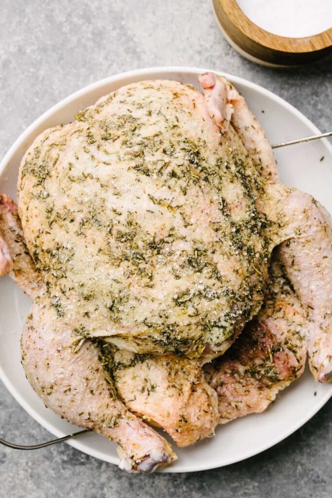 A whole chicken with garlic herb butter under the skin and salt and dried herbs all over the skin.