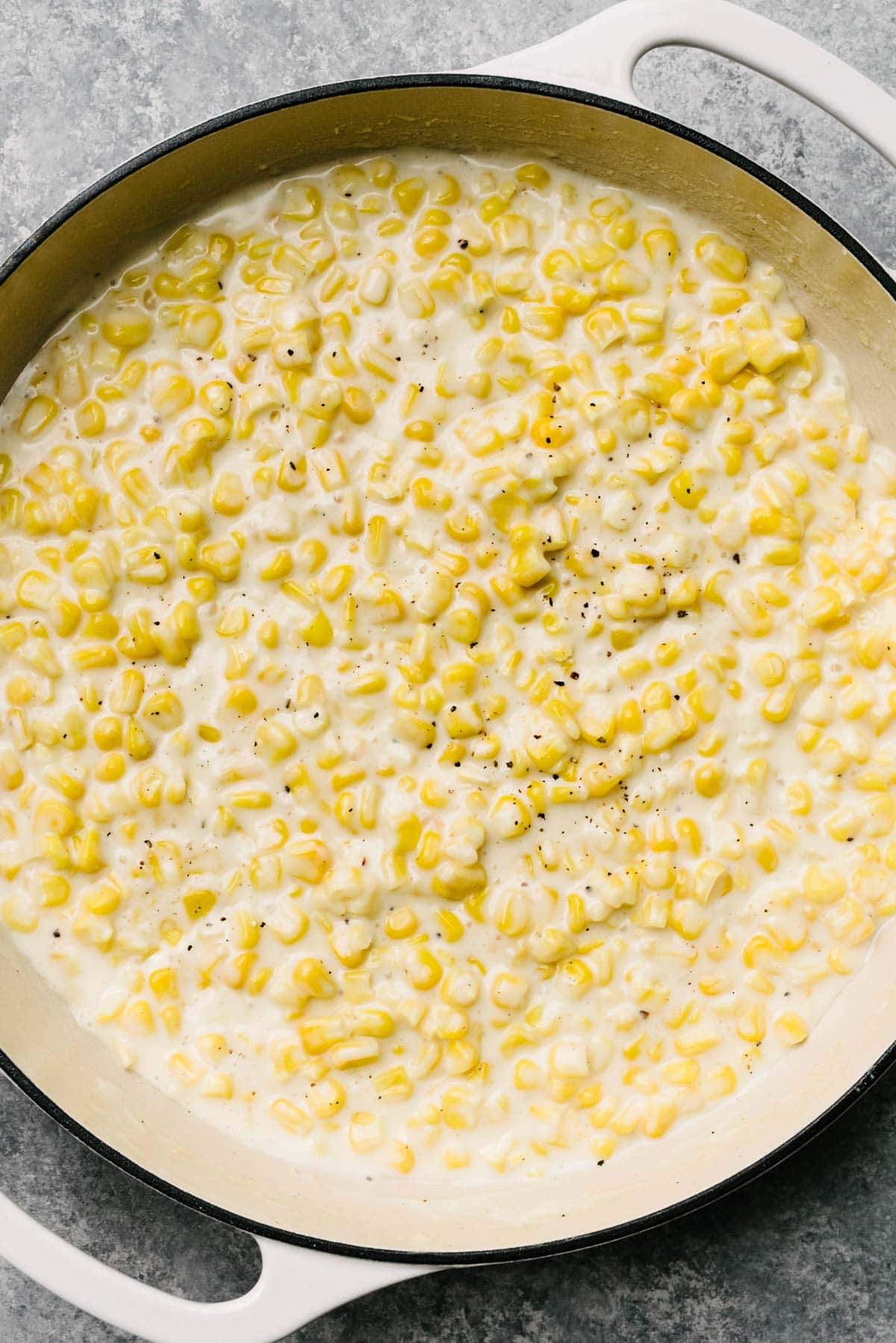 Creamed corn in a large grey enameled skillet.