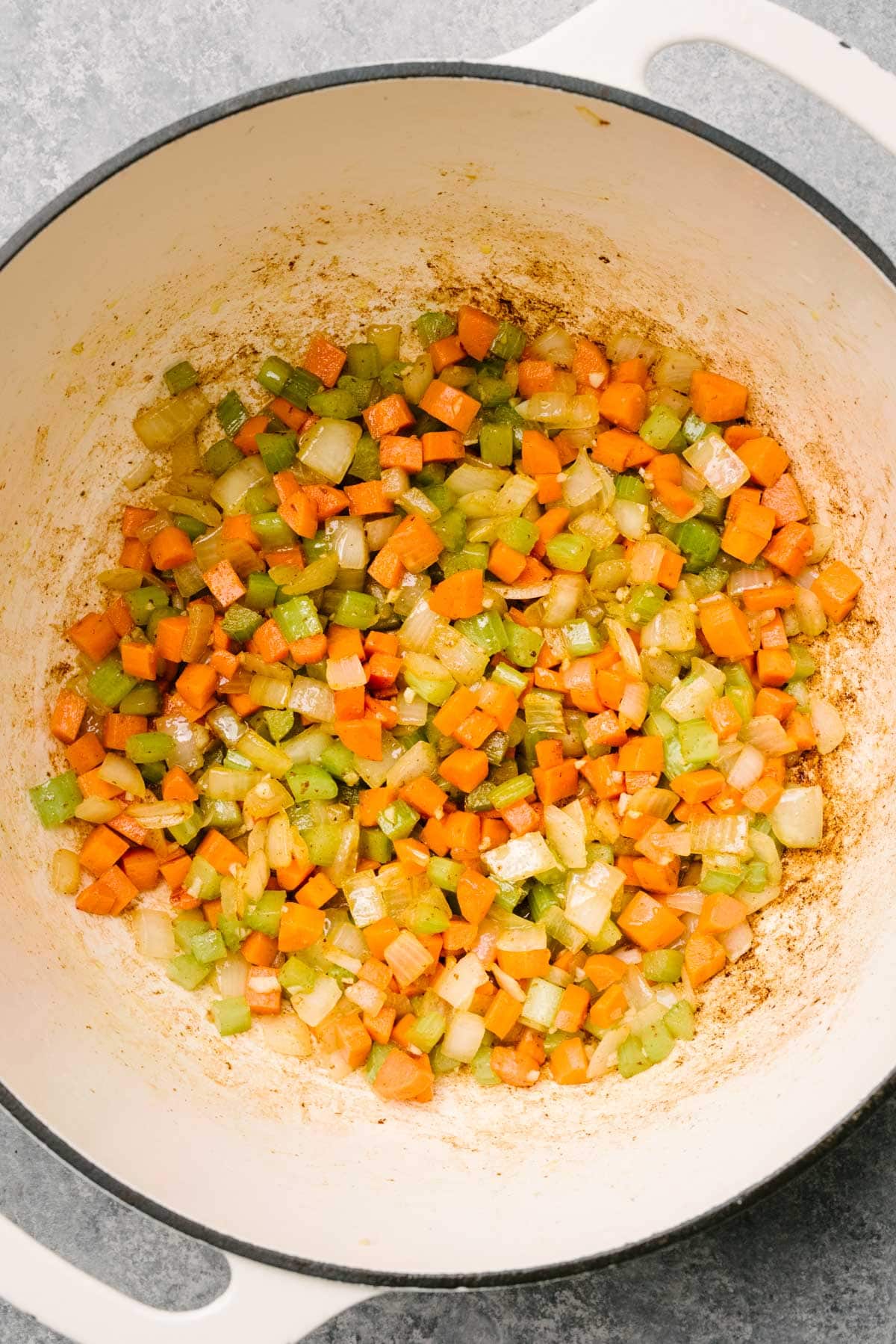 Sautéed onions, carrots, celery, and garlic in a white dutch oven.
