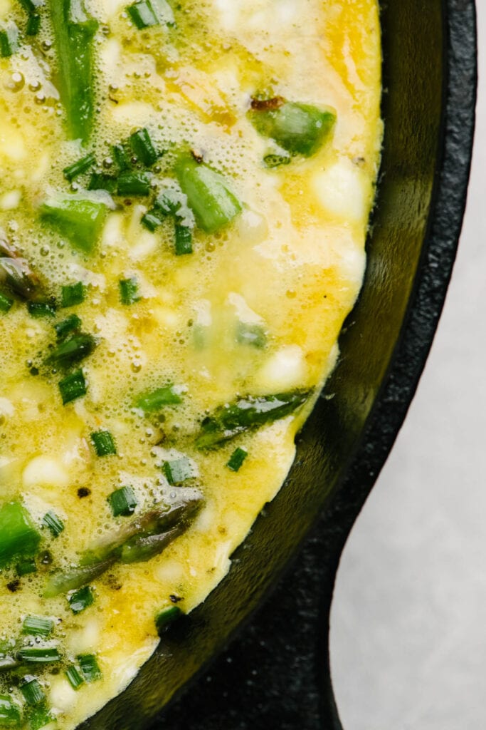 A detail shot of a partially cooked frittata showing the firm edges after cooking on the stove.
