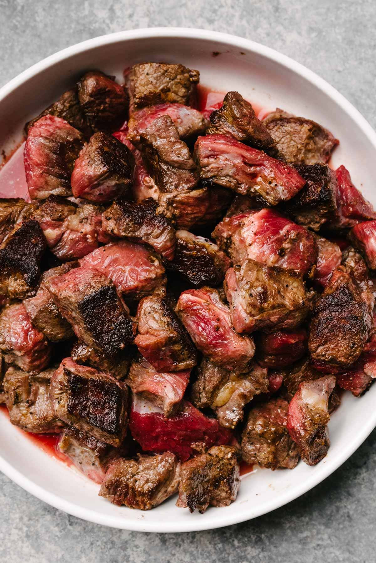 Seared pieces of stew meat on a white plate.