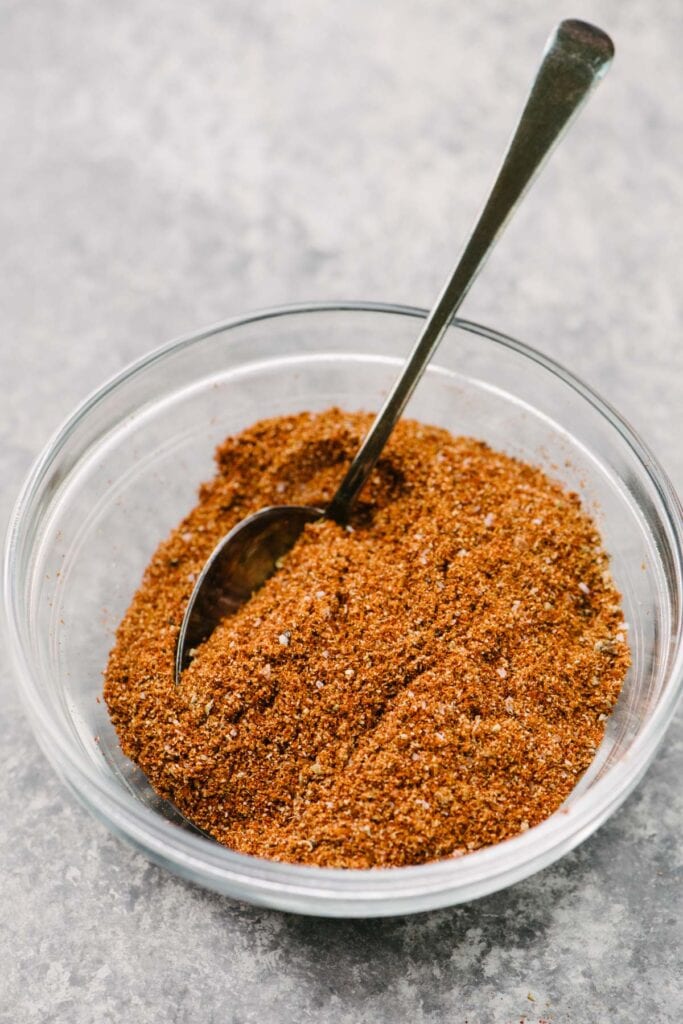 Side view, a small spoon tucked into a bowl of homemade taco seasoning.