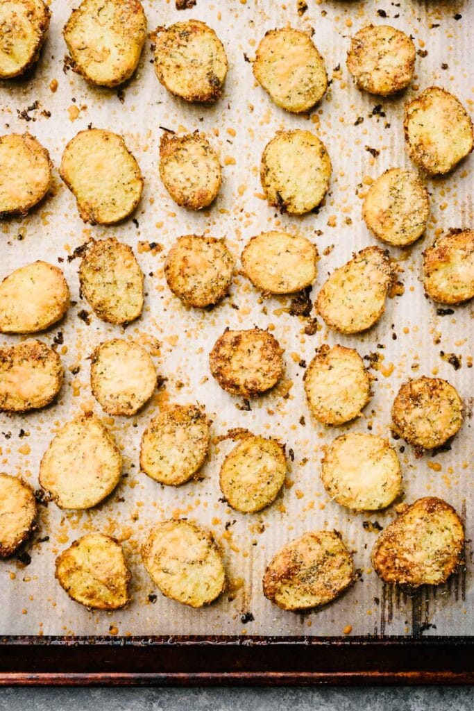 Parmesan crusted potatoes fresh from the oven on a parchment lined baking sheet.