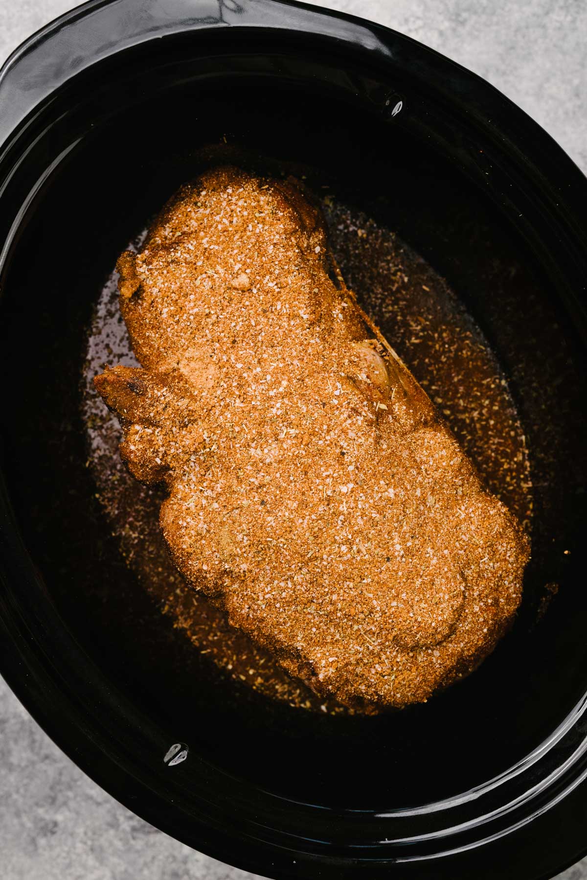 Dry rub sprinkled over a Boston butt pork roast in a crockpot.