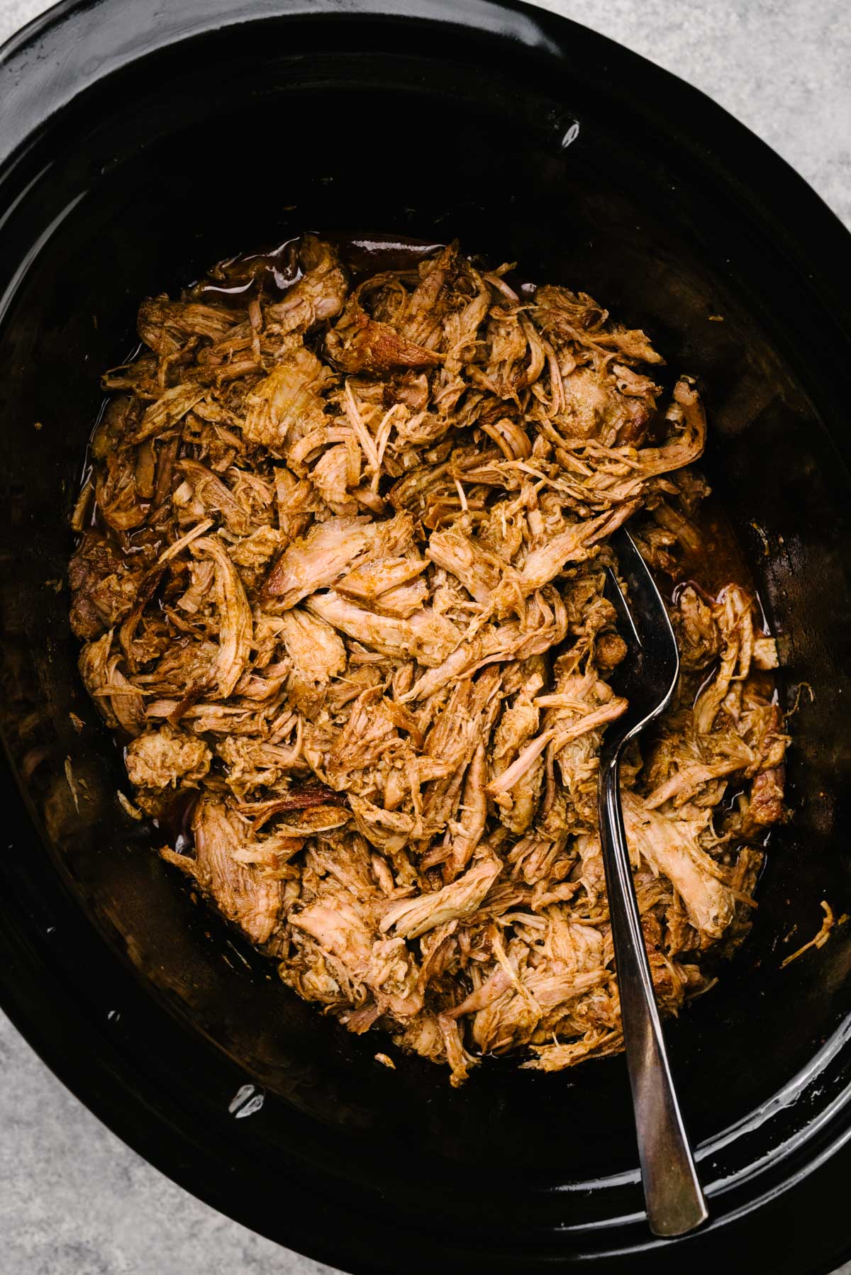 Shredded pulled pork in a crockpot tossed with pan juices.