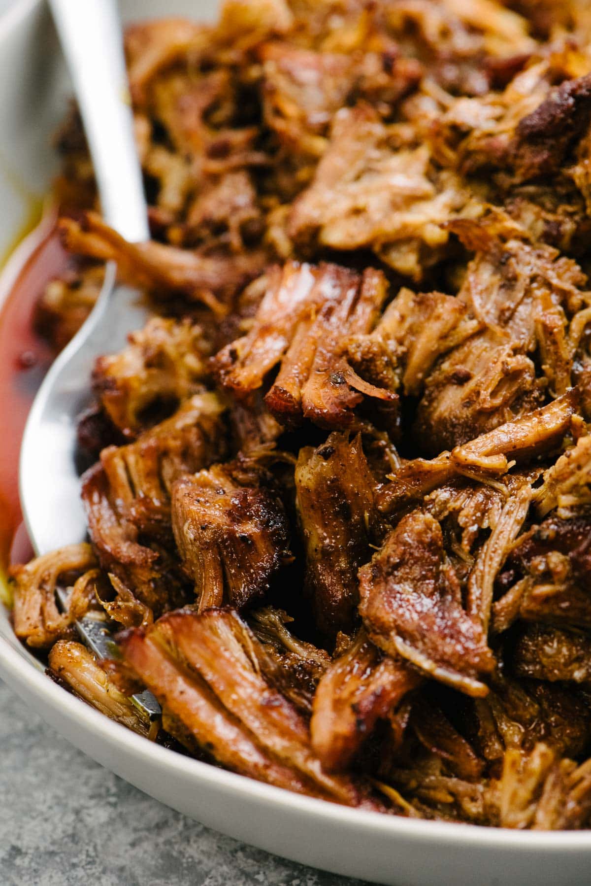 Side view, a silver serving fork tucked into a bowl of shredded Instant Pot pulled pork.