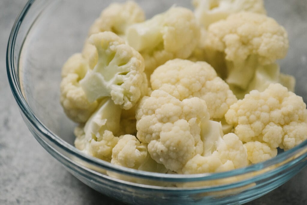 Side view, cauliflower cooked in the microwave in a glass mixing bowl.