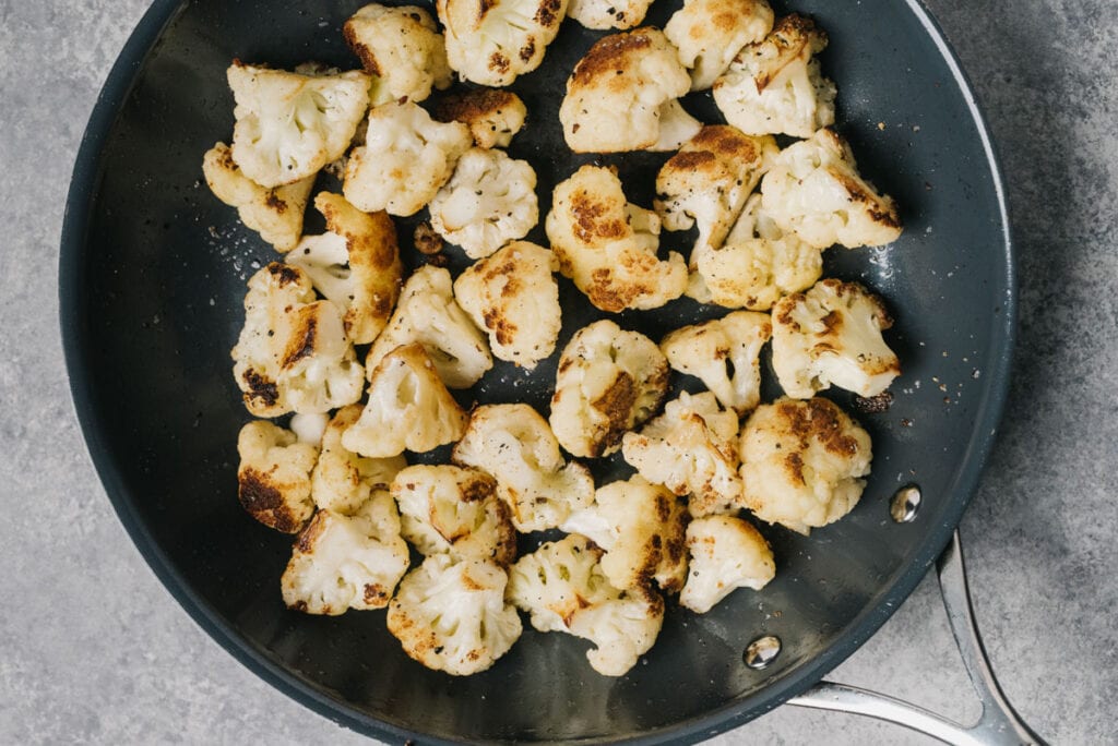 Sauteed cauliflower florets in a skillet.